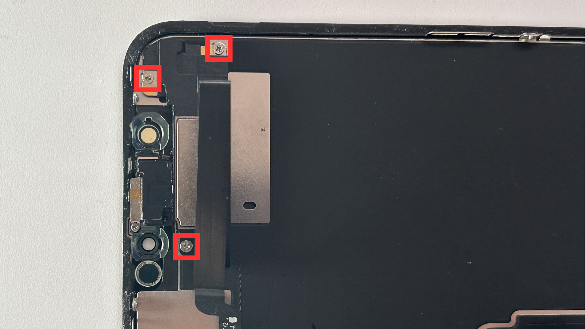 Close-up of the back-side of the screen showing the three screws holding the ear speaker to the screen