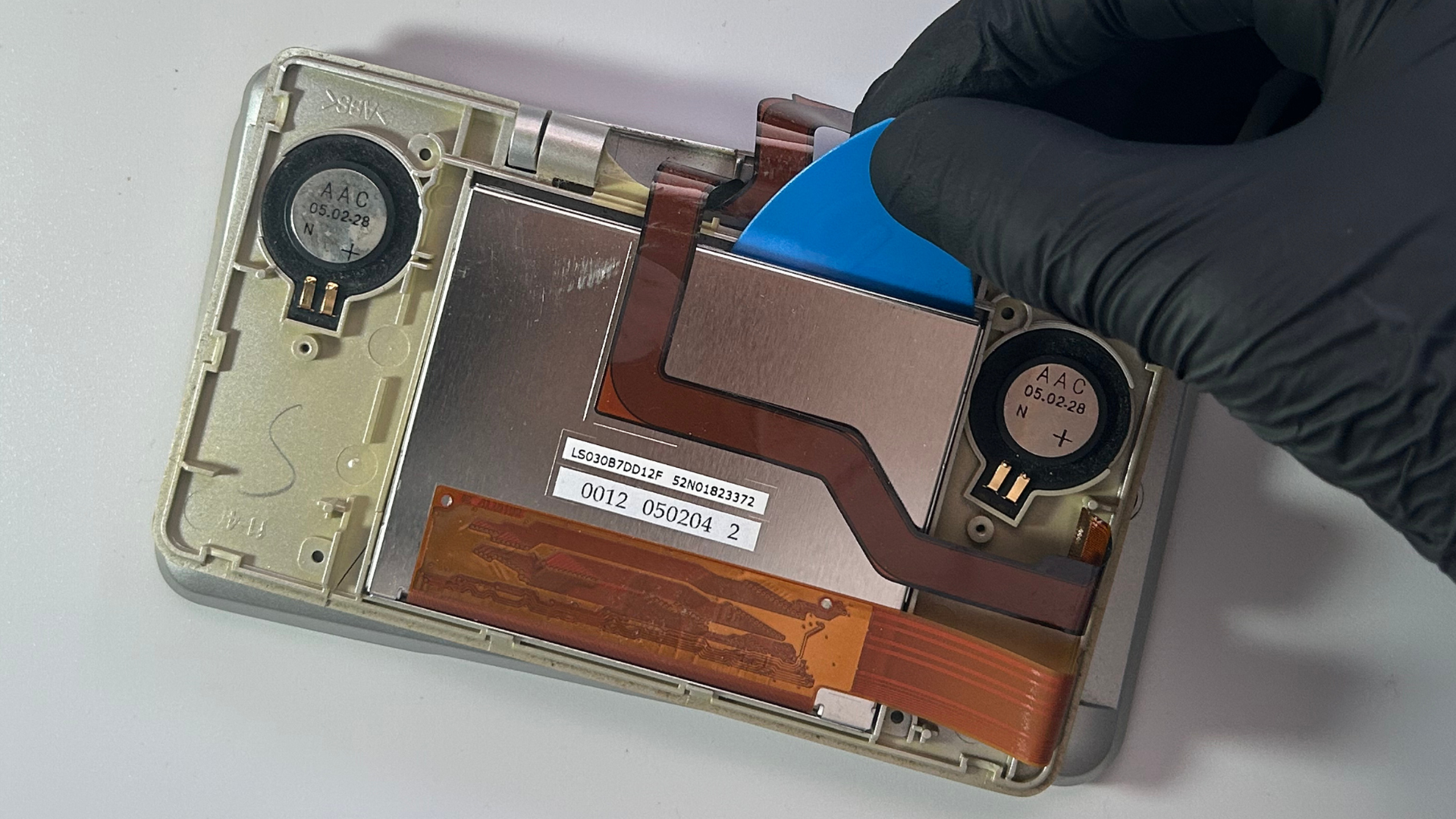 Plastic opening pick inserted between the Nintendo DS top LCD and surrounding frame