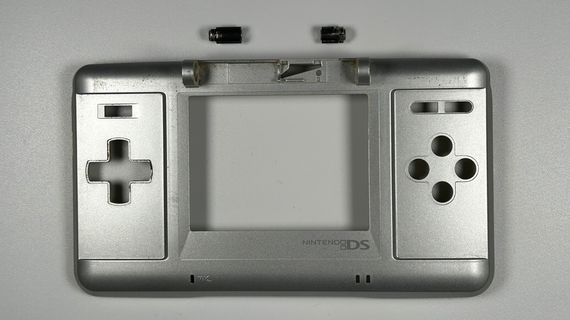 Nintendo DS hinge pieces removed and positioned above their corresponding slots in the lower chassis