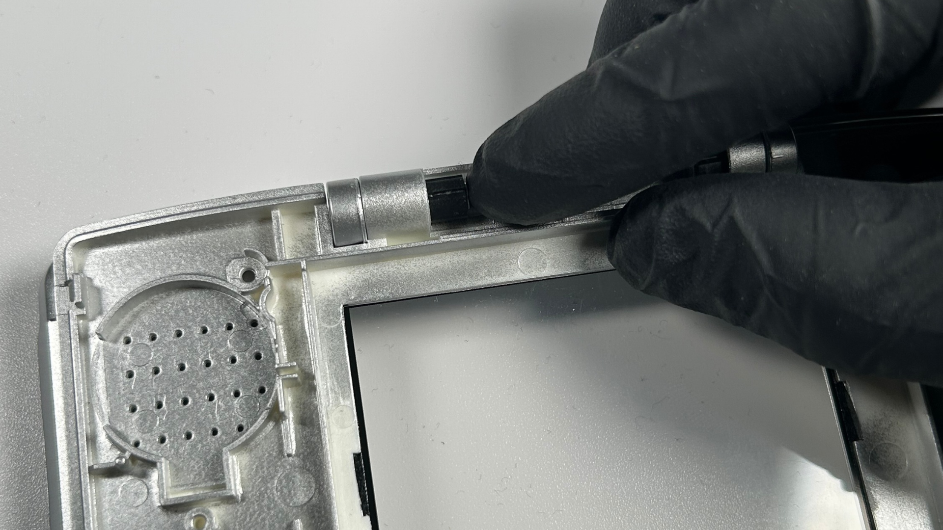 Installing the second black Nintendo DS hinge piece into the replacement shell