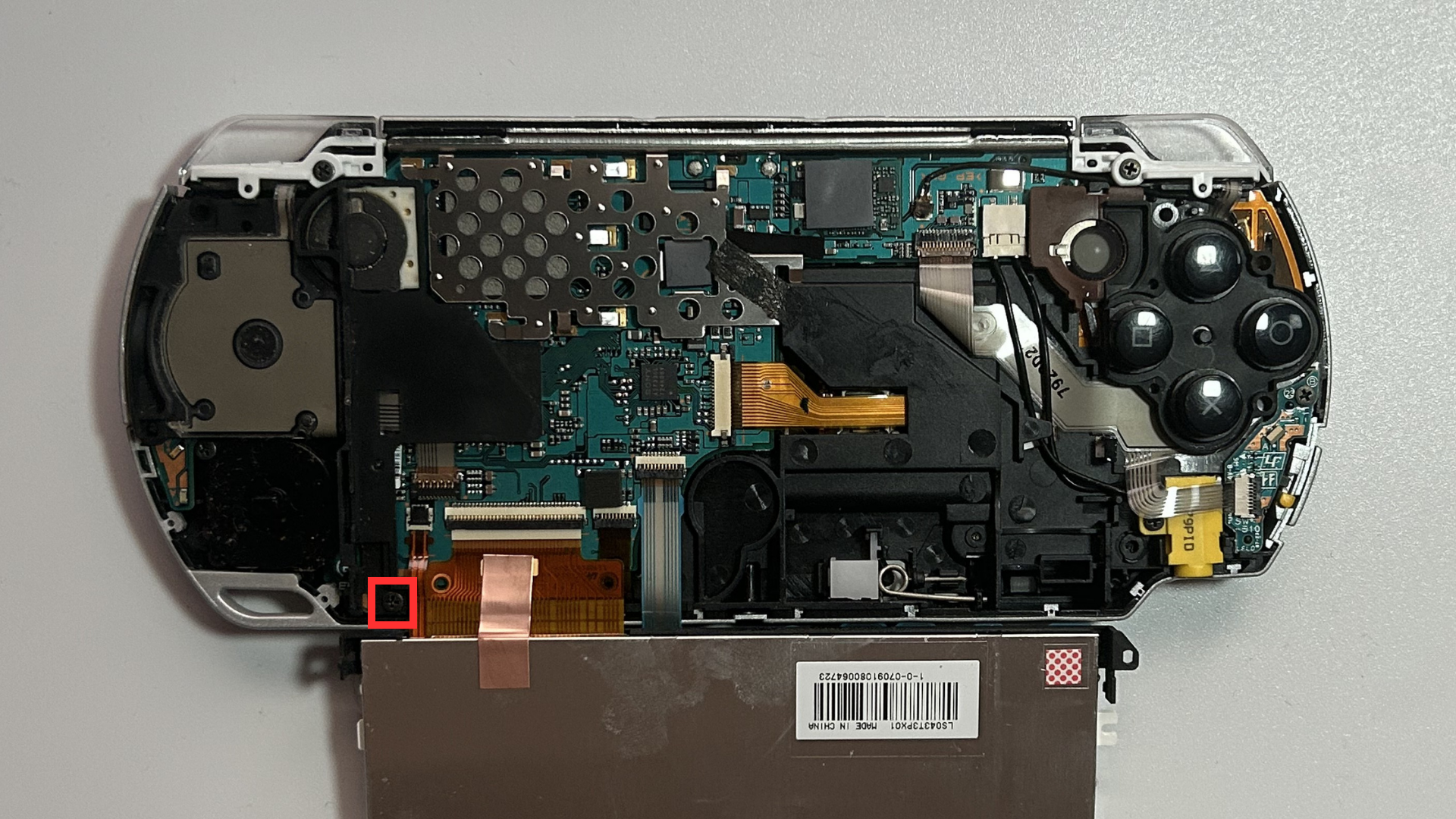 Phillips screw securing the black plastic thumbstick retaining clip inside a Sony PSP 2000