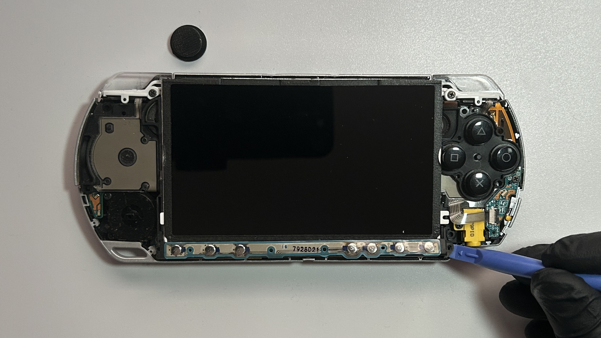 PSP 2000 control button strip being released from the opposite end of the LCD