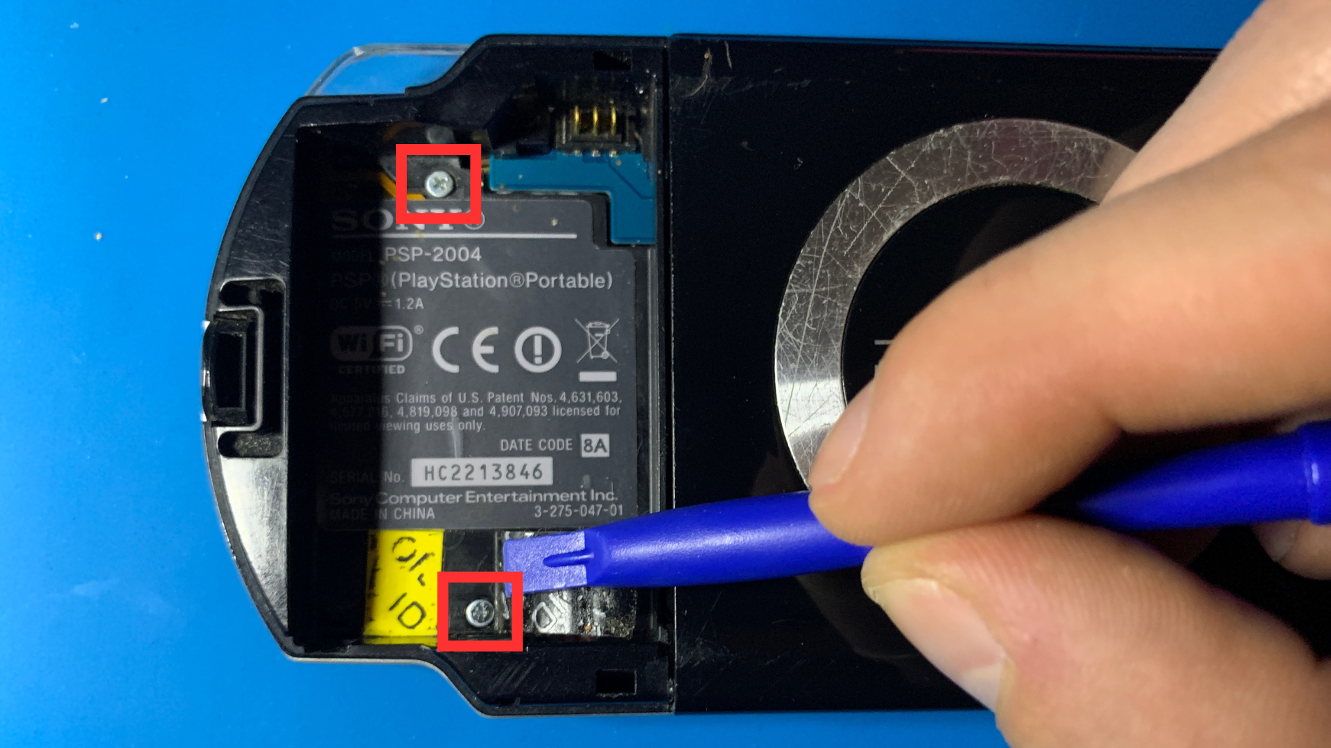 Close-up of hidden screw under the battery sticker on PSP 2000
