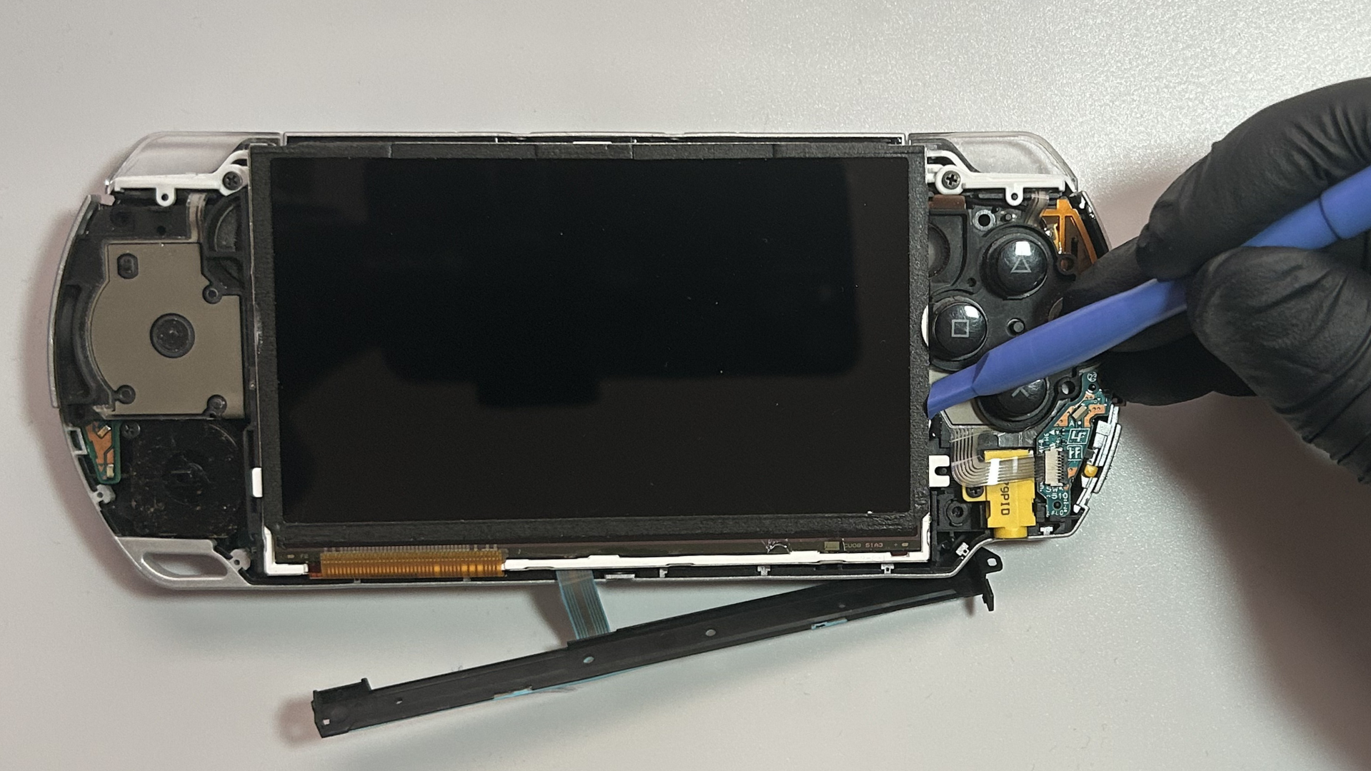 Pry tool gently prying notch on the right-side of LCD to release it