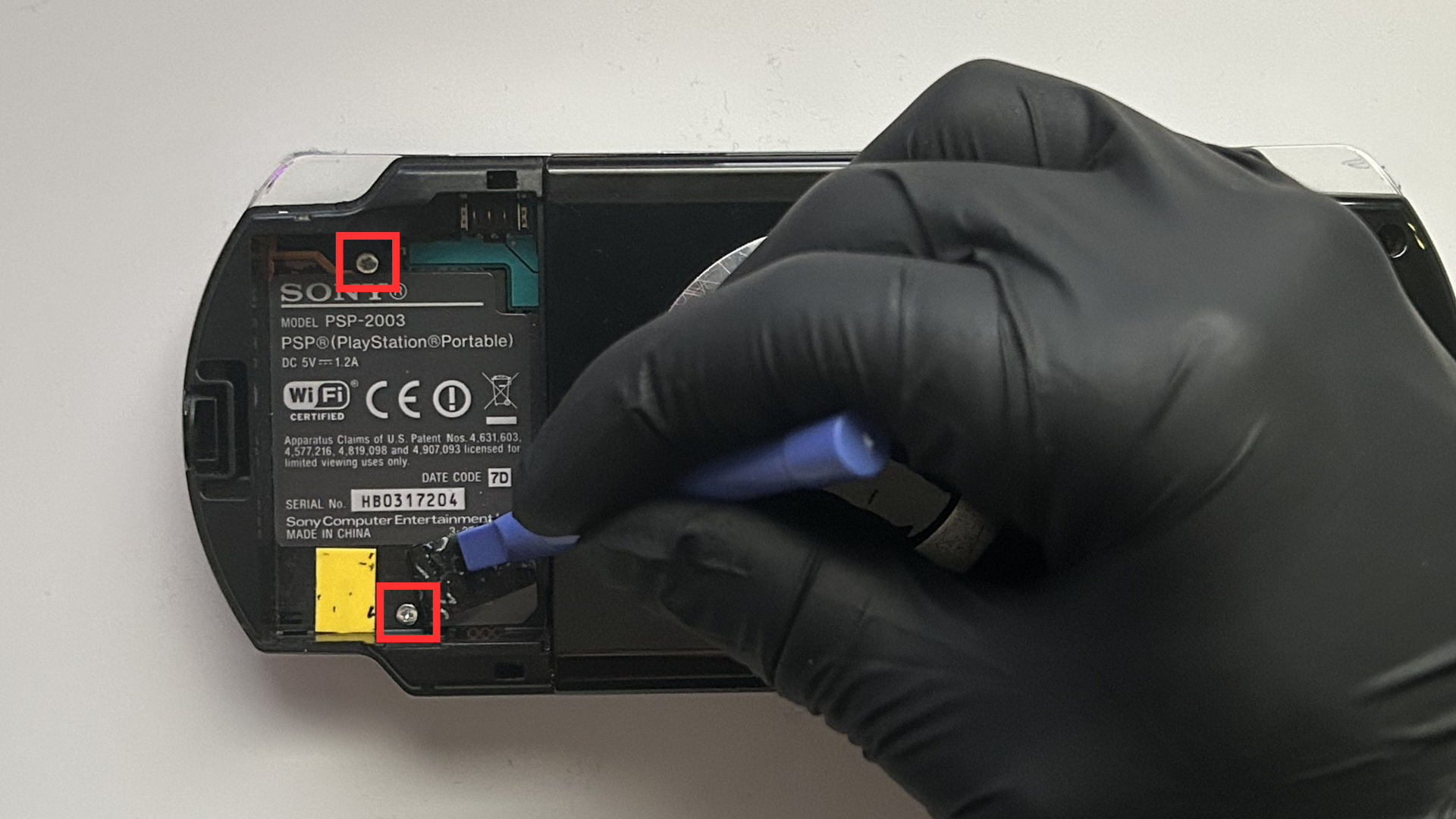 Close-up of hidden screw under the battery sticker on PSP 2000