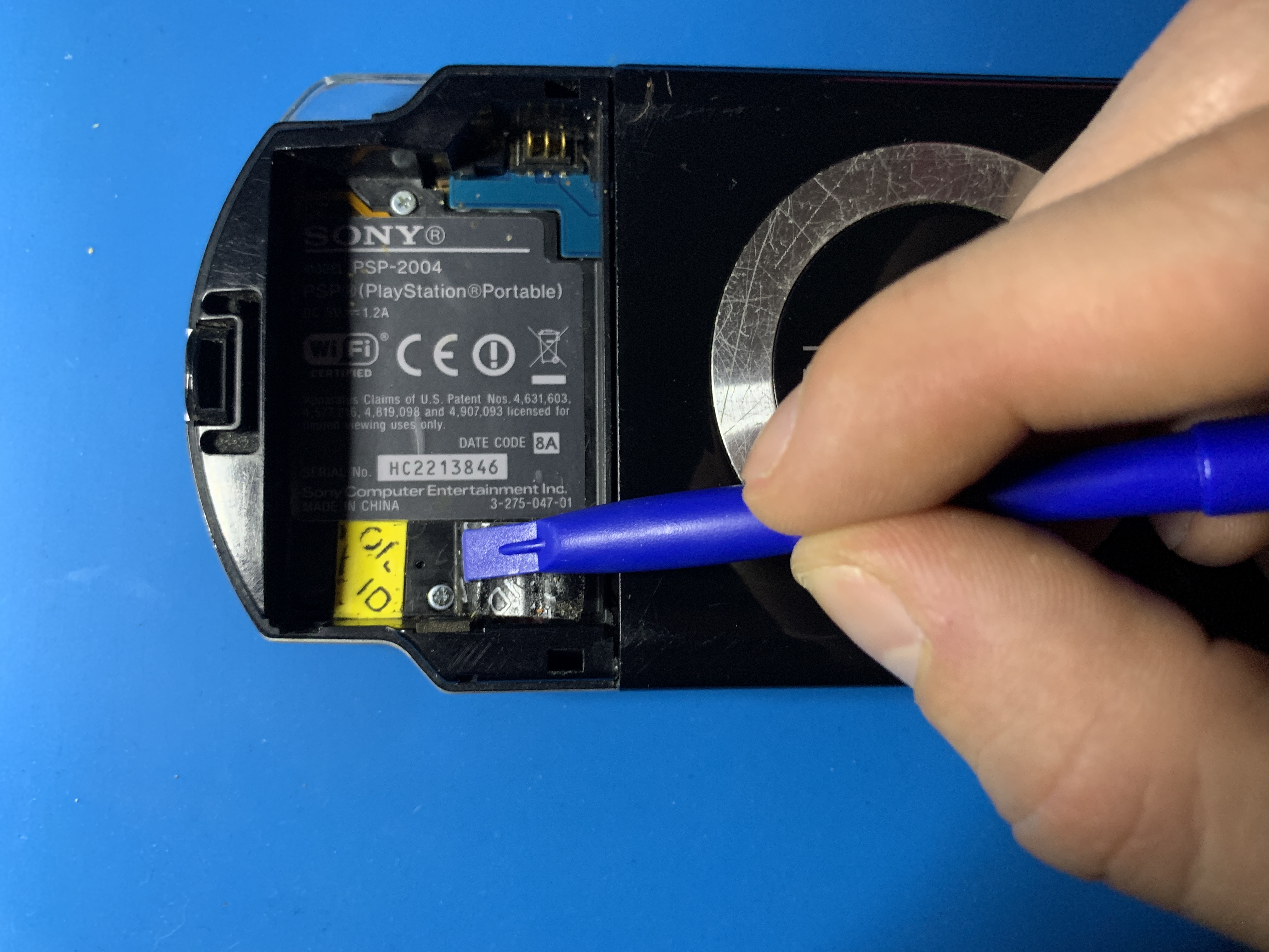 Close-up of hidden screw under the battery sticker on PSP 2000